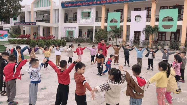 Học sinh tiểu học hăng hái giơ tay phát biểu trong giờ học âm nhạc, thể hiện sự hứng thú và thái độ tích cực.