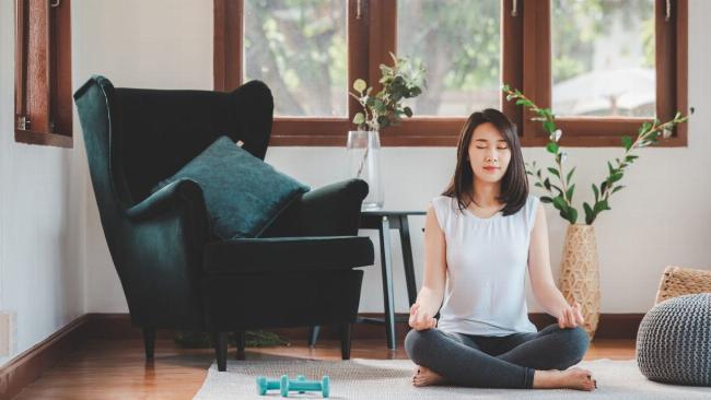 Một người đang ngồi thiền hoặc thư giãn với âm nhạc, cố gắng tìm kiếm sự bình yên nội tại.